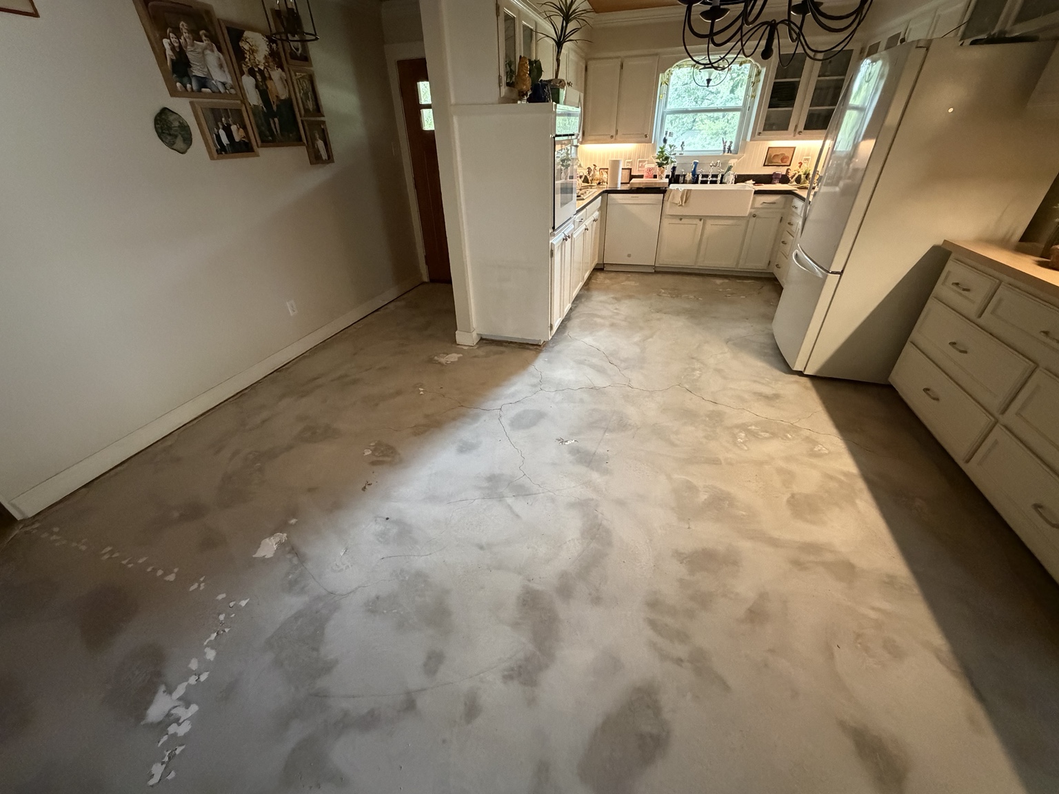 Kitchen view of the exposed concrete slab after tile removal in Joshua, Texas.